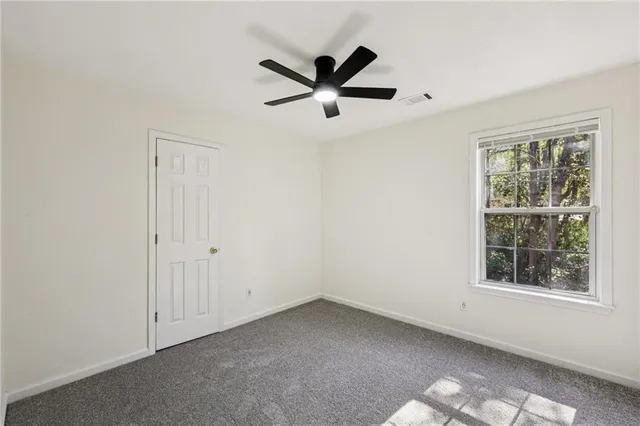 an empty room with window and ceiling fan