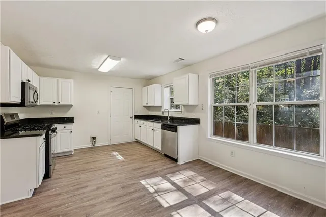a kitchen with granite countertop a stove top oven sink and cabinets