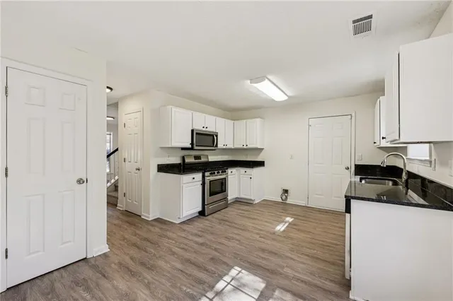 a kitchen with granite countertop a sink cabinets and stainless steel appliances