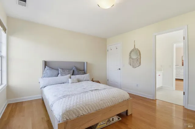 a spacious bedroom with a bed and wooden floor