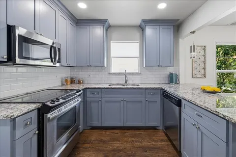 a kitchen with granite countertop a stove sink and cabinets