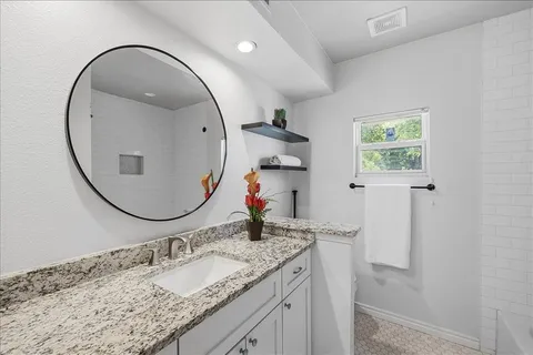 a en suite bathroom with a granite countertop sink and a mirror