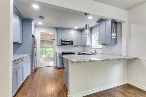 a large kitchen with stainless steel appliances granite countertop a stove a sink and a refrigerator