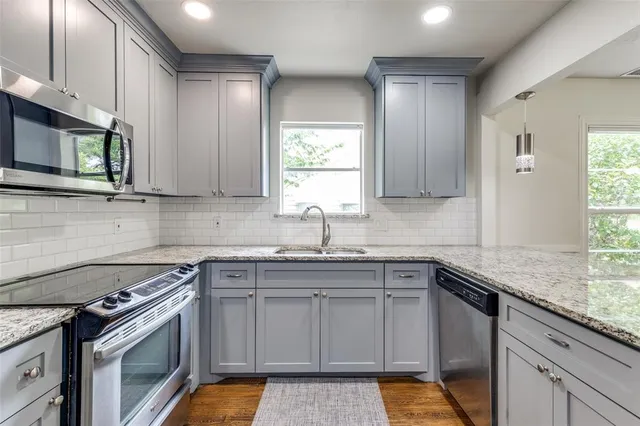 a kitchen with stainless steel appliances granite countertop a sink stove cabinets and a window