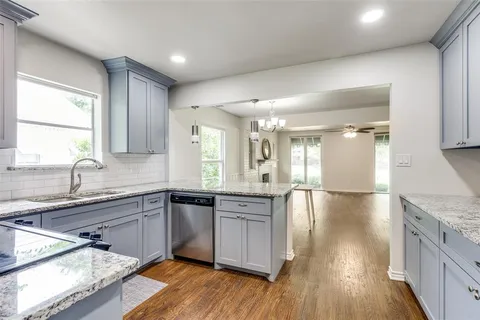 a large kitchen with granite countertop a sink and cabinets with wooden floor