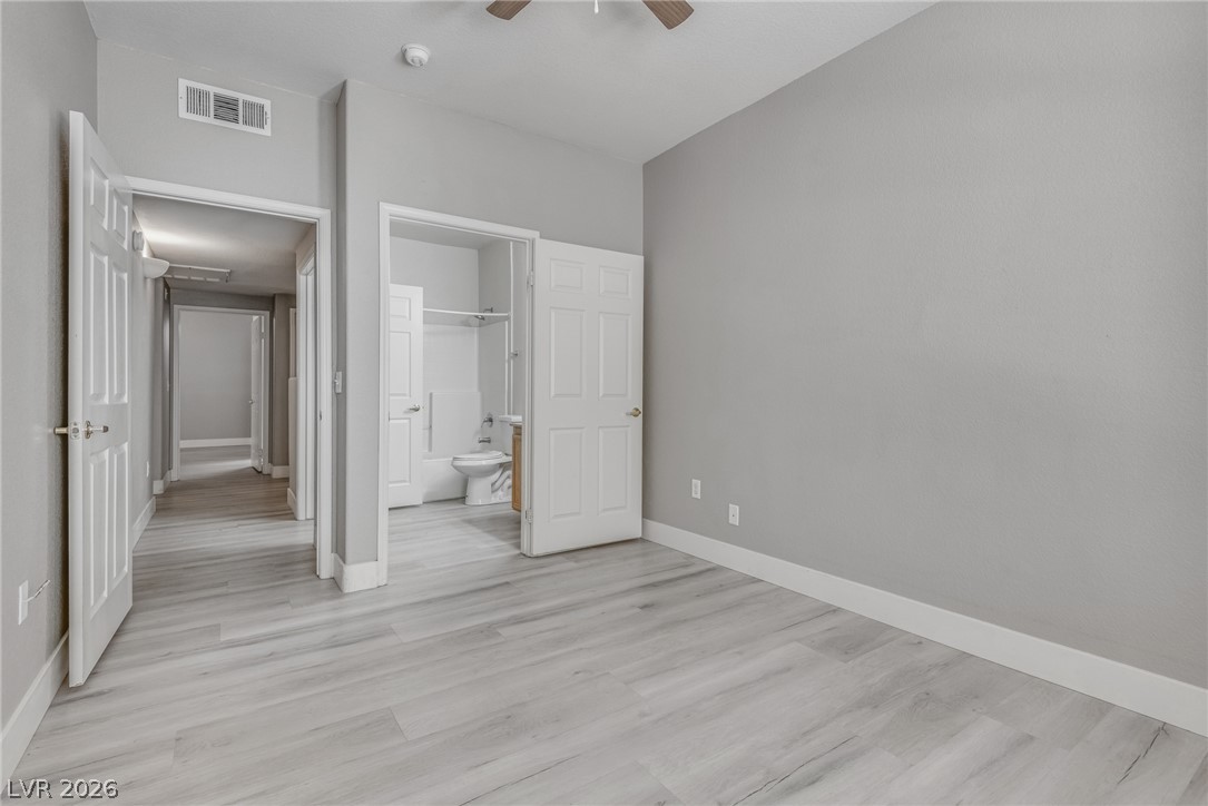 10550 West Alexander Road, Unit 1139 Las Vegas, NV 89129 - Photo 17 of 27 A well-lit bedroom with stylish flooring and a convenient en-suite bathroom.