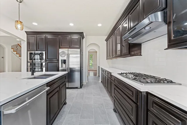 a kitchen with stainless steel appliances granite countertop a stove a sink and a refrigerator