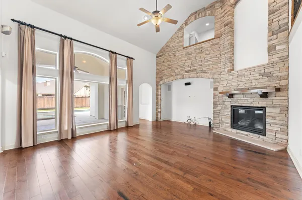 an empty room with wooden floor a fireplace and windows