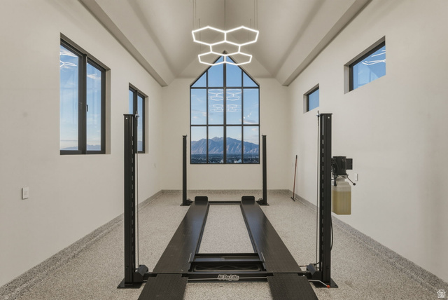 923 North Emery Lane Elk Ridge, UT 84651 - Photo 81 of 101 Automotive lift system within a spacious garage featuring a vaulted ceiling and an expansive multi-pane window framing a mountain backdrop