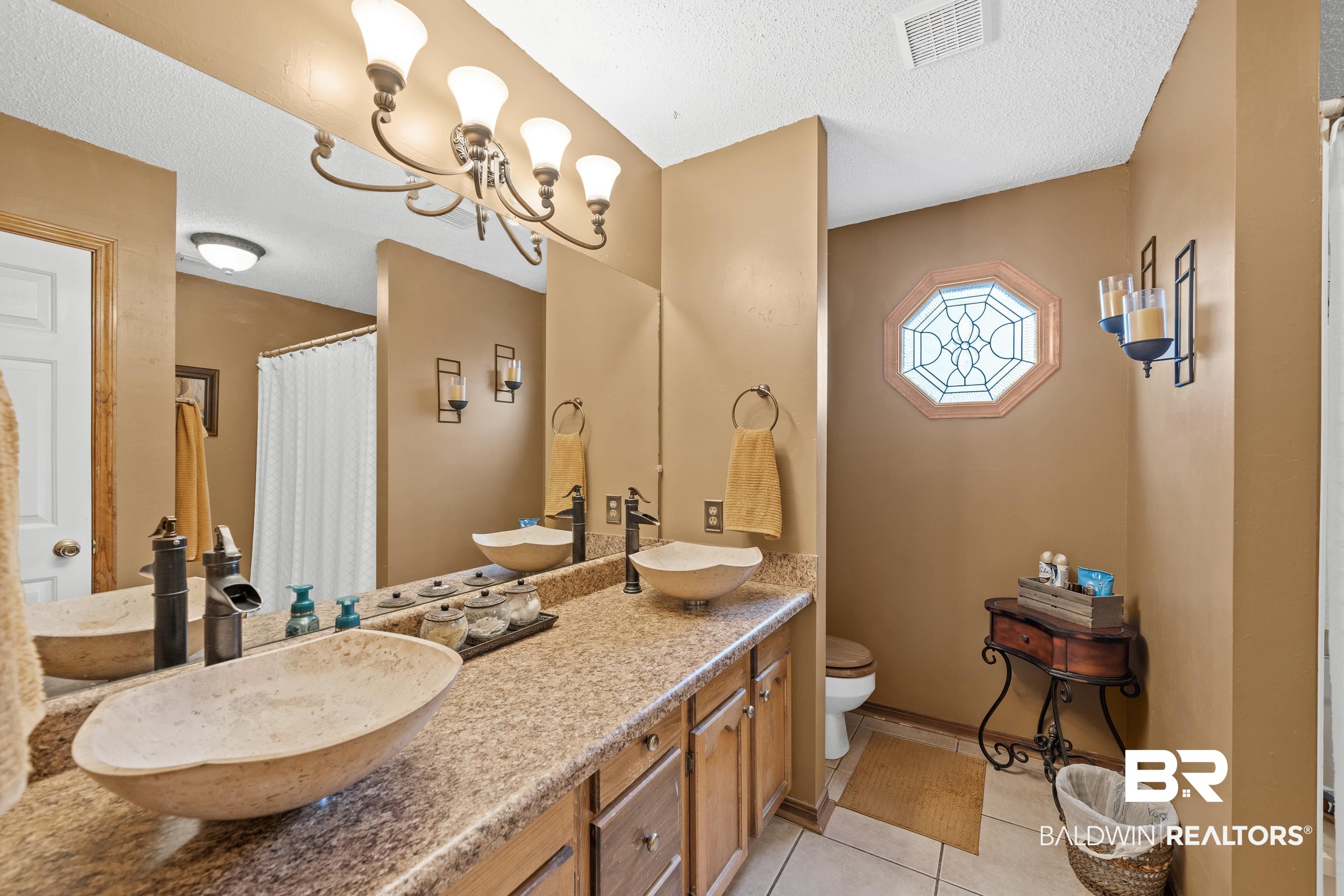 460 Ridgewood Drive Daphne, AL 36526 - Photo 20 of 31 Bathroom with toilet, vanity, a notable chandelier, tile patterned floors, and a textured ceiling