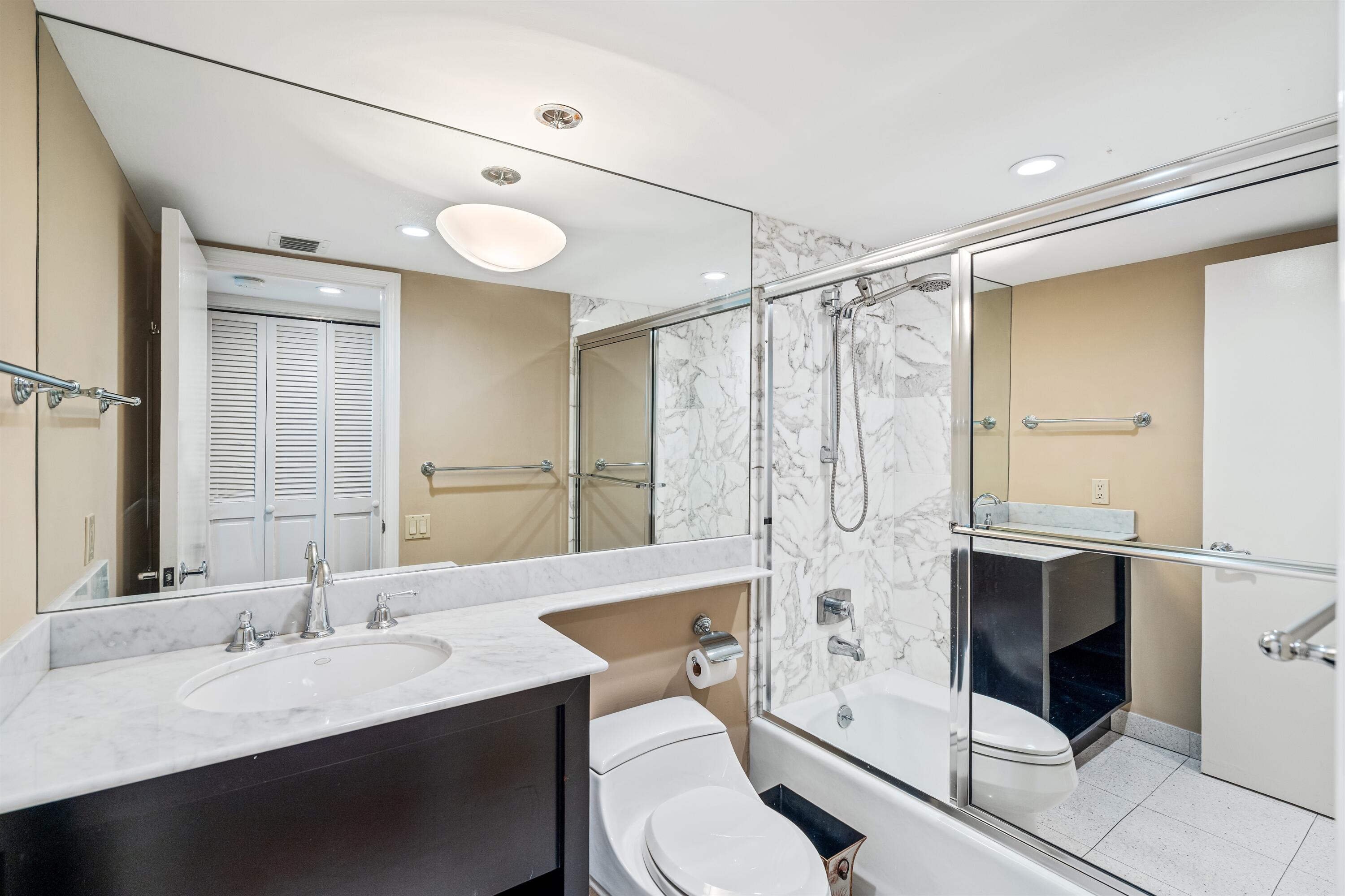 350 South Ocean Boulevard, Unit 12C Boca Raton, FL 33432 - Photo 23 of 50 a bathroom with a double vanity sink toilet mirror and shower