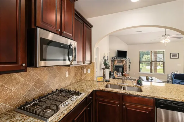 a kitchen with stainless steel appliances granite countertop a stove a sink and a microwave