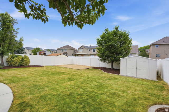 2223 North Pointe Meadow Loop Lehi, UT 84048 - Photo 42 of 56 Spacious backyard featuring a manicured lawn, white vinyl fencing, a gravel-filled area, a storage shed, and mature trees