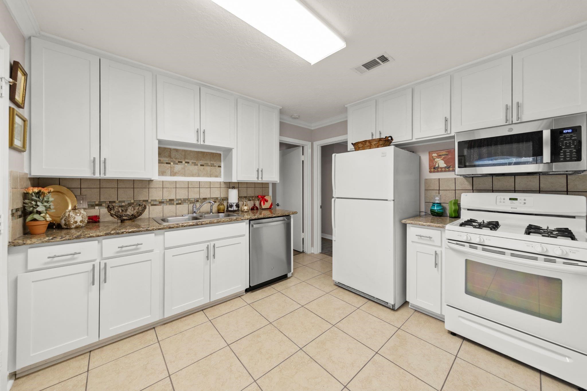10128 Homestead Road Houston, TX 77016 - Photo 3 of 9 a kitchen with granite countertop cabinets and white appliances