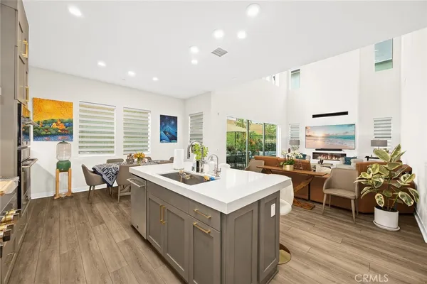 a kitchen with granite countertop a stove a sink dishwasher a dining table and chairs with wooden floor