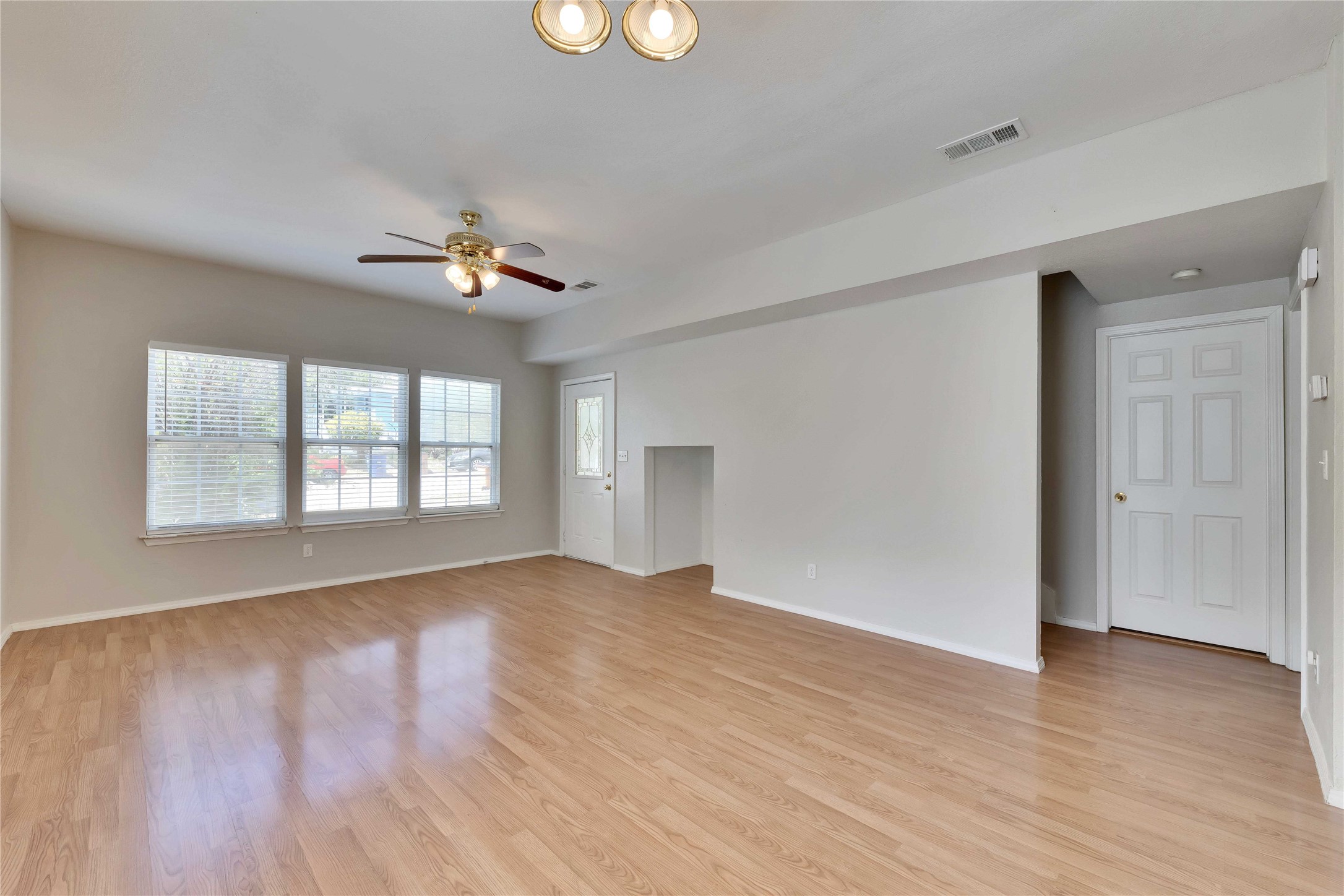2201 East 18th Street, Unit B Austin, TX 78702 - Photo 3 of 25 A well-lit living space features light-toned wood flooring and a refreshing ceiling fan.