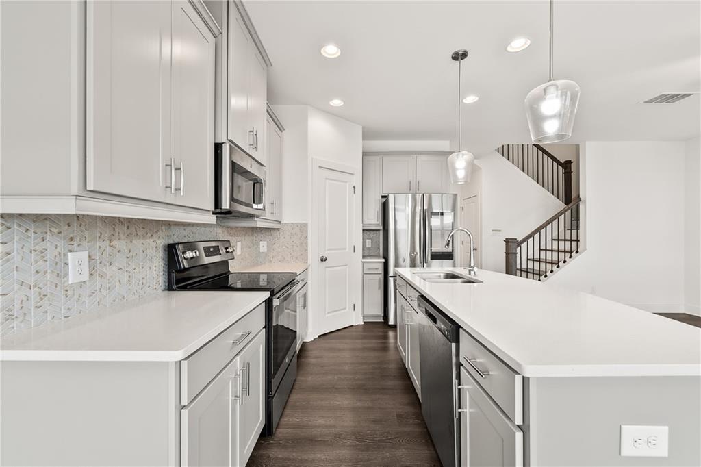 98 Auburn Valley Way Auburn, GA 30011 - Photo 16 of 47 a kitchen with white cabinets appliances and wooden floor