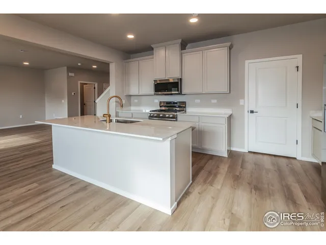 a kitchen with wooden floors and white stainless steel appliances