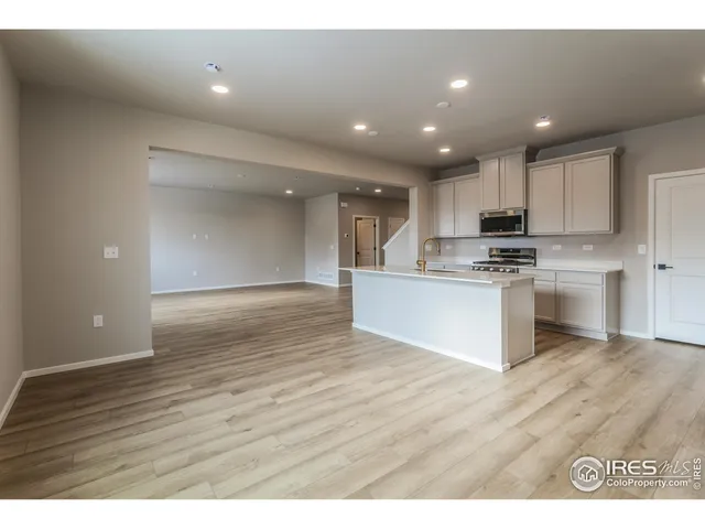 a view of kitchen with kitchen island granite countertop stainless steel appliances refrigerator sink and cabinets