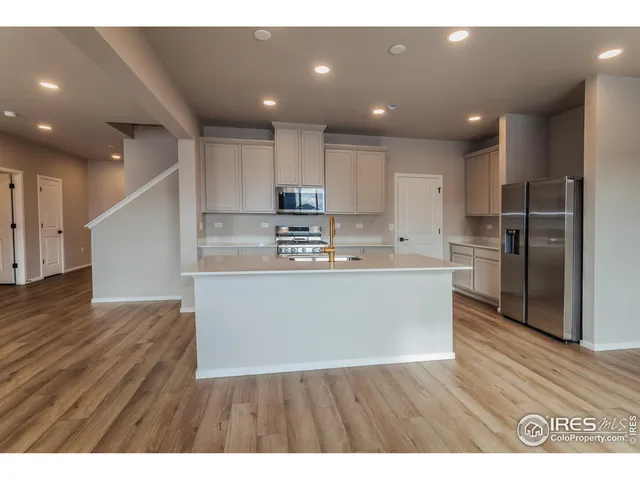 a view of kitchen with kitchen island wooden floors appliances and center island