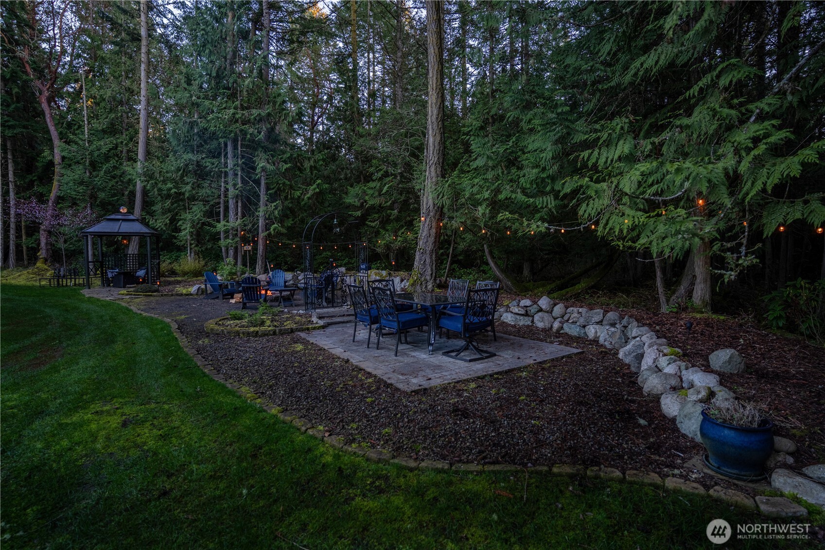 72 Doe Place Sequim, WA 98382 - Photo 34 of 40 a view of a patio with table and chairs potted plants and large trees