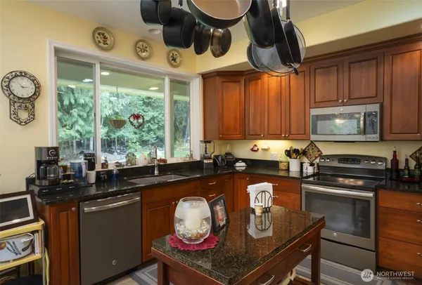 a kitchen with stainless steel appliances granite countertop a stove a sink and a microwave