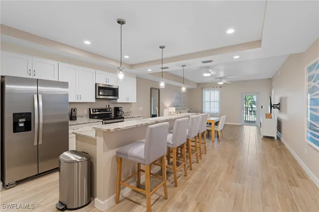 a kitchen with stainless steel appliances granite countertop a dining table chairs refrigerator and microwave