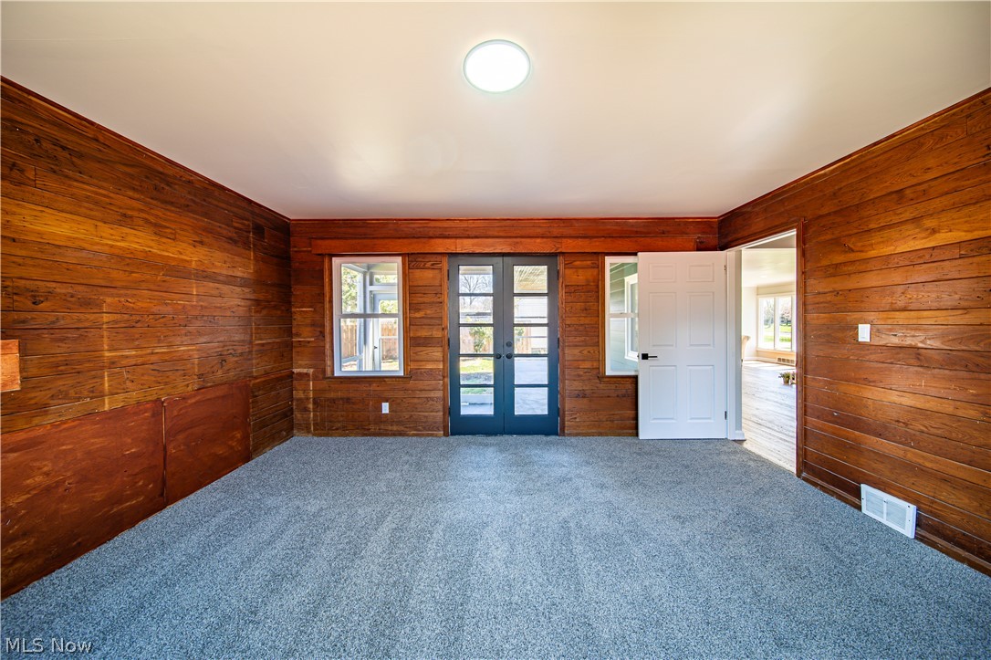 9412 Oakdale Road Parma, OH 44129 - Photo 13 of 38 Empty room with french doors, wood walls, and dark colored carpet