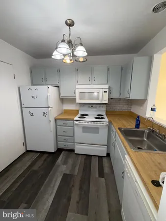 a kitchen with a stove a chandelier and a refrigerator