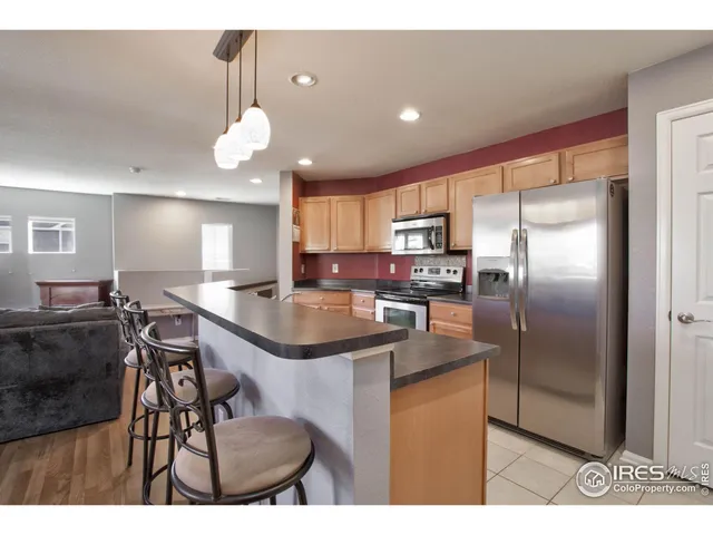 a kitchen with stainless steel appliances granite countertop a sink a stove a refrigerator cabinets and a dining table