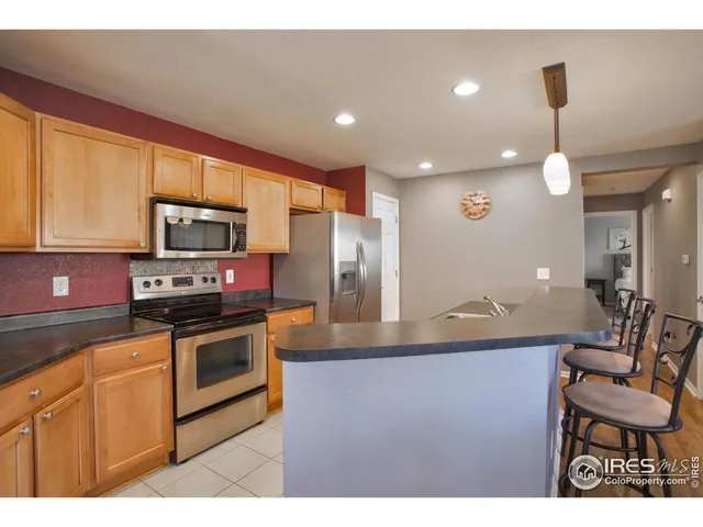 a kitchen with stainless steel appliances granite countertop a sink a stove a microwave a refrigerator and cabinets