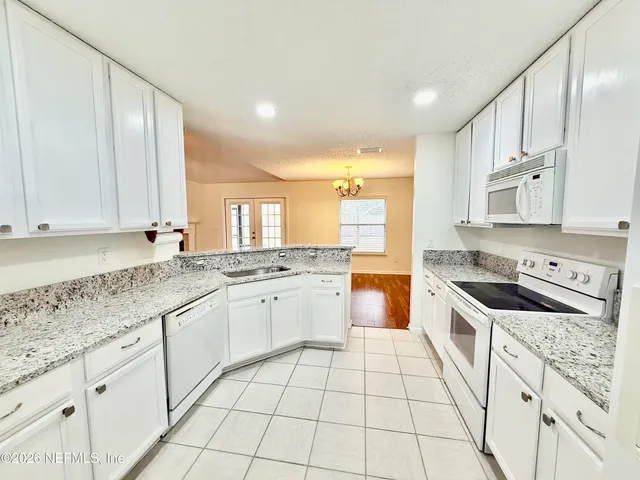 a large kitchen with stainless steel appliances granite countertop a stove a sink and white cabinets