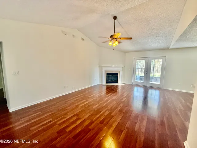 a view of empty room with wooden floor and fan