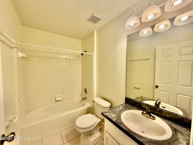 a bathroom with a granite countertop sink toilet mirror and bathtub