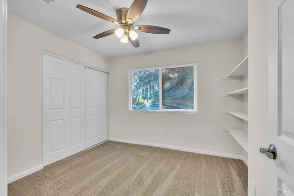an empty room with windows and fan