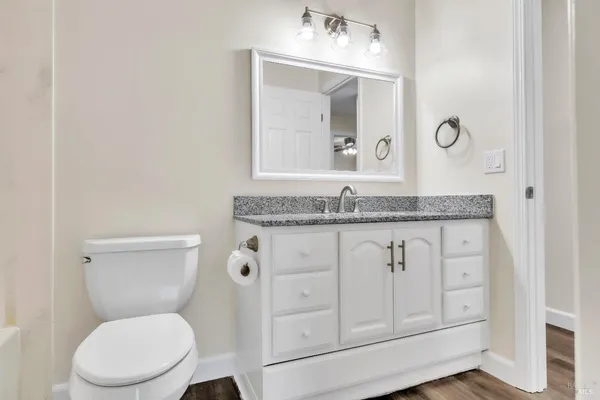 a bathroom with a granite countertop toilet sink and mirror