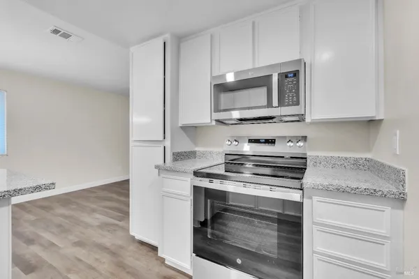 a kitchen with cabinets stainless steel appliances and wooden floor