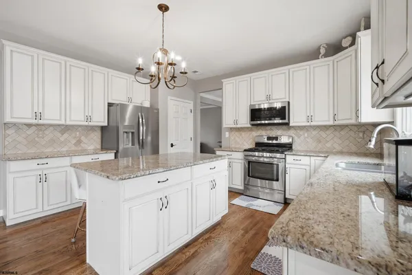 a kitchen with stainless steel appliances granite countertop a stove refrigerator and cabinets