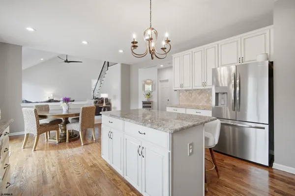 a kitchen with stainless steel appliances granite countertop a refrigerator a microwave oven a sink and a dining table with wooden floor