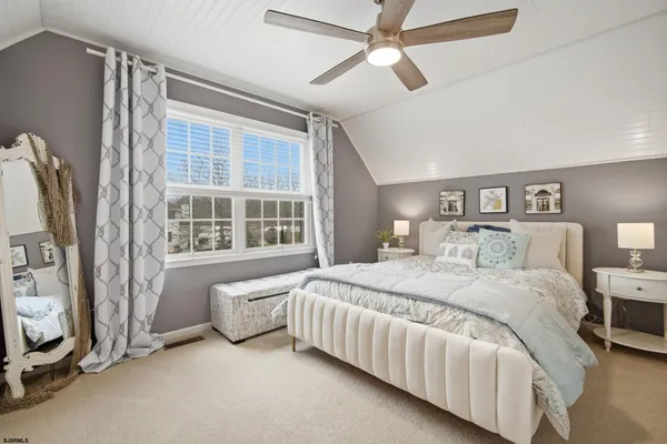 a large bed sitting in a bedroom next to a window and a chandelier