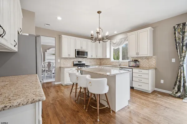 a kitchen with kitchen island granite countertop a sink a counter space appliances and cabinets