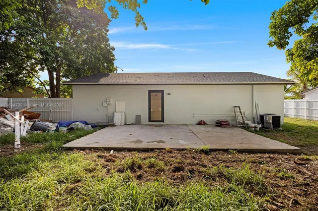 a backyard of a house with large trees and plants