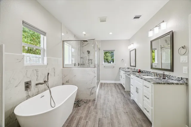 a spacious bathroom with a double vanity sink a mirror and a bathtub