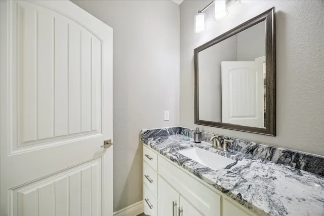 a bathroom with a granite countertop sink and a mirror