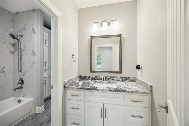 a bathroom with a granite countertop sink tub and a mirror