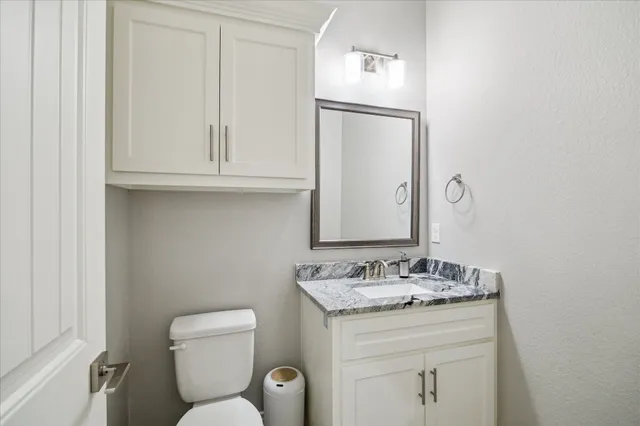 a bathroom with a granite countertop toilet sink and mirror