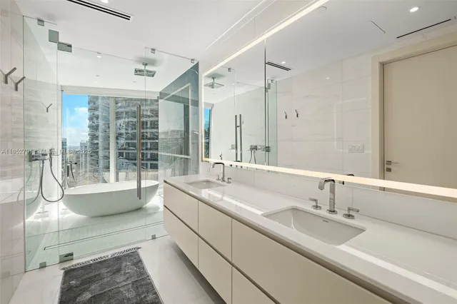 a bathroom with a double vanity sink and mirror with bathtub