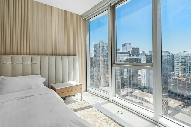 a bedroom with a bed and a large window with outer view