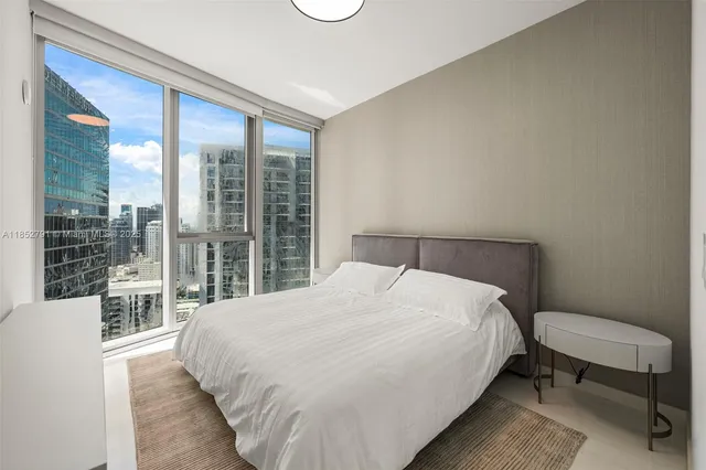 a bedroom with a bed lamp and a large window