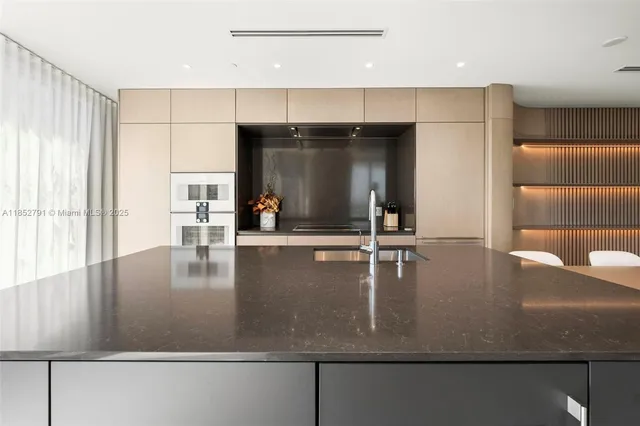 a view of a kitchen with kitchen island a large counter top space a sink stainless steel appliances and cabinets